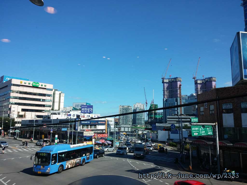 The blue bus is on the road, secluded past, and sky blue.